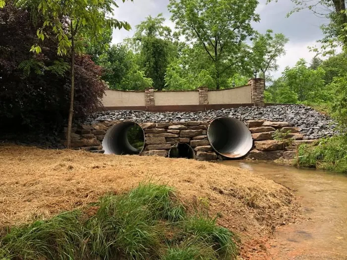 Twin culvert pipes set in a stacked stone headwall at a creek crossing