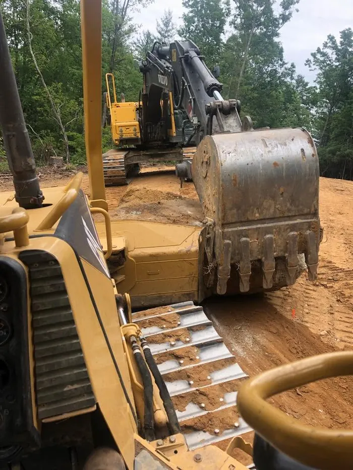 Dozer and tracked excavator working together on a red clay cut